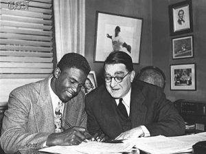 Jackie Robinson singing a contract with Branch Rickey and the Brooklyn Dodgers in 1947 to break the color barrier